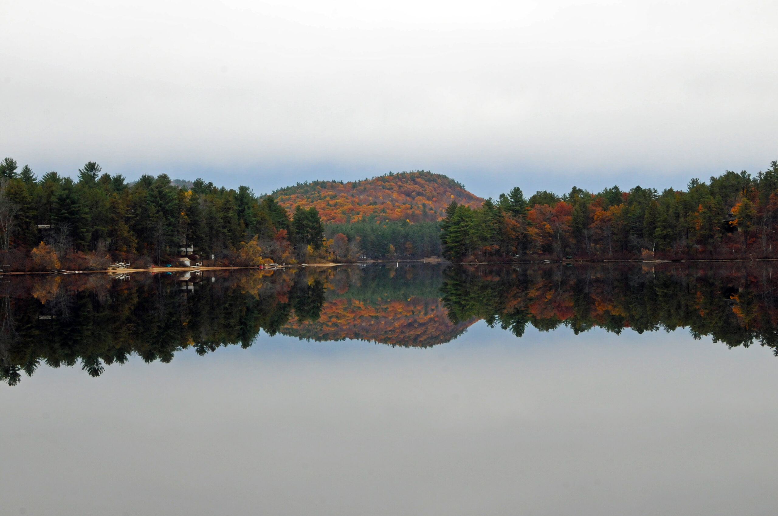 A view of Danforth Bay in the fall showing a glassy calm lake.